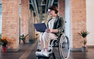 a woman in a wheelchair working on her laptop